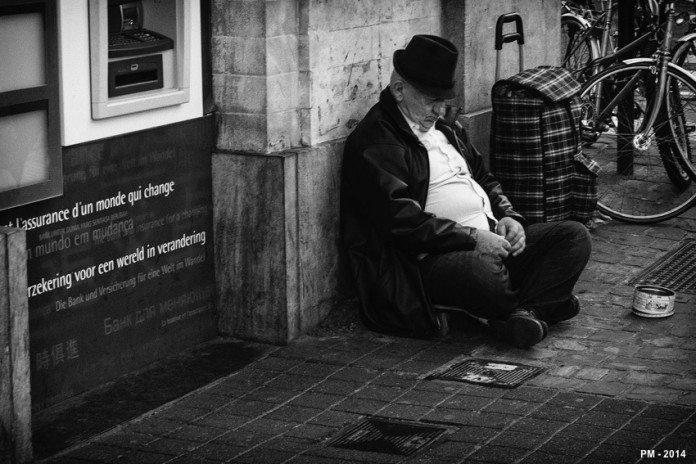 保険会社の前で座り込む男性